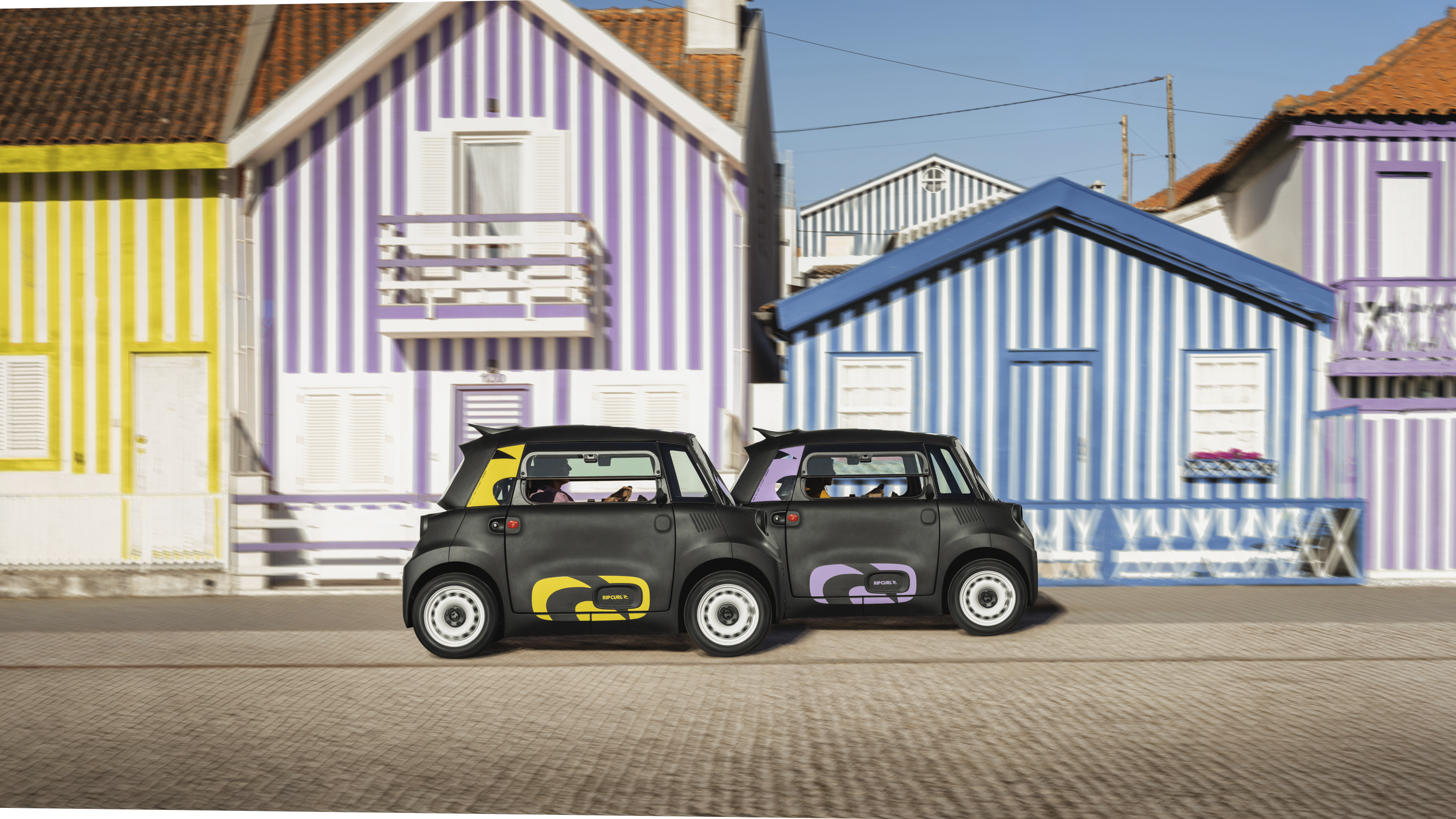 Vue de rue côte à côte de la Citroën Ami x Rip Curl électrique sans permis, style double Citroën Ami pour voiture électrique urbaine